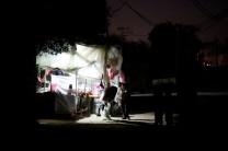 A Palestinian boy stands outside a makeshift grocery shop lit with a lamp powered by a battery during a power cut in Beit Lahiya in the northern Gaza Strip.