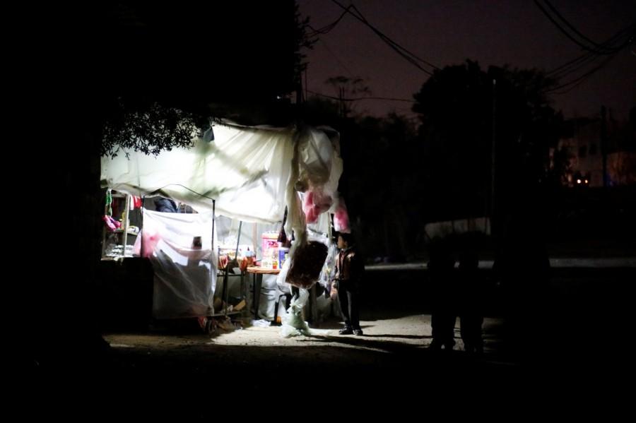 A Palestinian boy stands outside a makeshift grocery shop lit with a lamp powered by a battery during a power cut in Beit Lahiya in the northern Gaza Strip. Lights out in Gaza,Gaza Lights out,darkened streets,Beit Lahiya,northern Gaza Strip