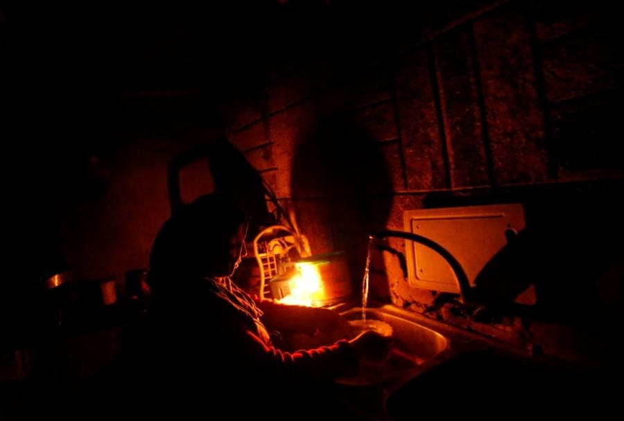 A Palestinian woman uses a candle light as she washes up in her kitchen during a power cut inside her house in Beit Lahiya in the northern Gaza Strip. Lights out in Gaza,Gaza Lights out,darkened streets,Beit Lahiya,northern Gaza Strip