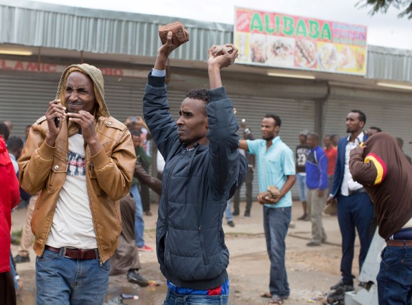 Somali immigrants hold rocks during clashes in Pretoria, South Africa, February 24, 2017. Police fired tear gas, water cannon and rubber bullets to disperse rival marches by hundreds of protesters in Pretoria on Friday, after mobs looted stores this week believed to belong to immigrants. Somali immigrants,South African,Nigerian migrant,Pretoria,South African mobs,immigrants attack