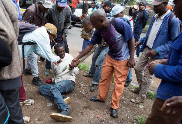 A man holds his South African identity document after being attacked by a mob in Pretoria, South Africa, February 24, 2017. Police fired tear gas, water cannon and rubber bullets to disperse rival marches by hundreds of protesters in Pretoria on Friday, after mobs looted stores this week believed to belong to immigrants. Somali immigrants,South African,Nigerian migrant,Pretoria,South African mobs,immigrants attack