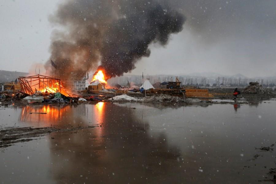 Buildings burn after being set alight by protesters preparing to evacuate the main opposition camp against the Dakota Access oil pipeline near Cannon Ball, North Dakota. Standing Rock,Last stand at Standing Rock,Dakota Access pipeline,Dakota Access