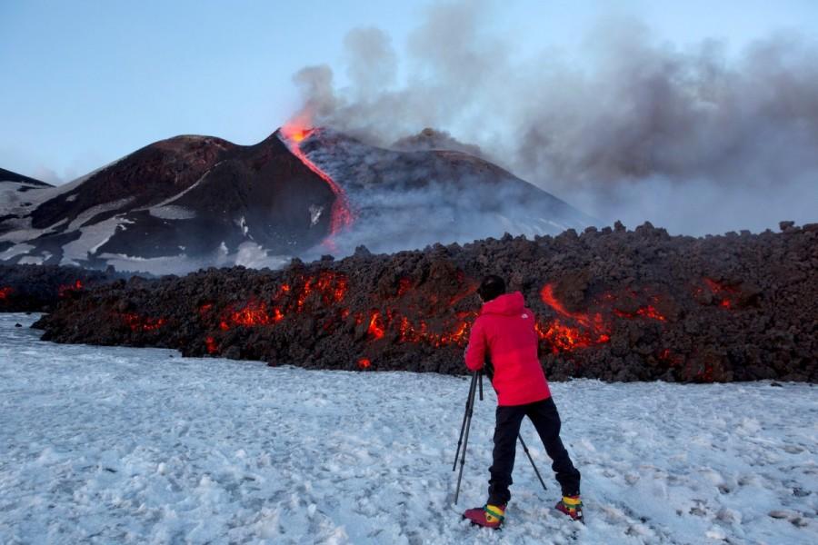 A tourist stands in front of Italy's Mount Etna, Europe's tallest and most active volcano, as it spews lava during an eruption on the southern island of Sicily, Italy February 28, 2017. Mount Etna erupts,Mount Etna,Volcano's Eruptions,Volcano Eruptions,Volcano,lava,Italy