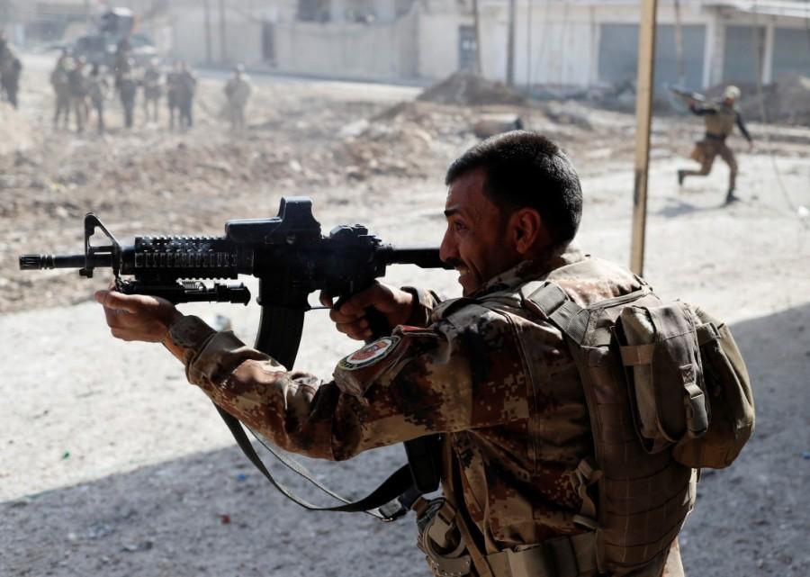 An Iraqi special forces soldier fires a rifle as other soldiers runs across a street during a battle in Mosul, Iraq March 1, 2017. Tigris river,Brutal street,Mosul,U.S,Islamic State,damaged bridge,Iraqi special forces,Iraqi forces,Iraqi special forces in Mosul