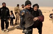 Khatla Ali Abdullah, 90, a displaced Iraqi women who fled her home, is carried by a member of the Iraqi forces in the desert in western Mosul, Iraq.