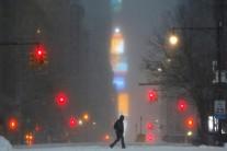 Times Square is seen in the background as a man walks along West 59th street in falling snow in Manhattan.