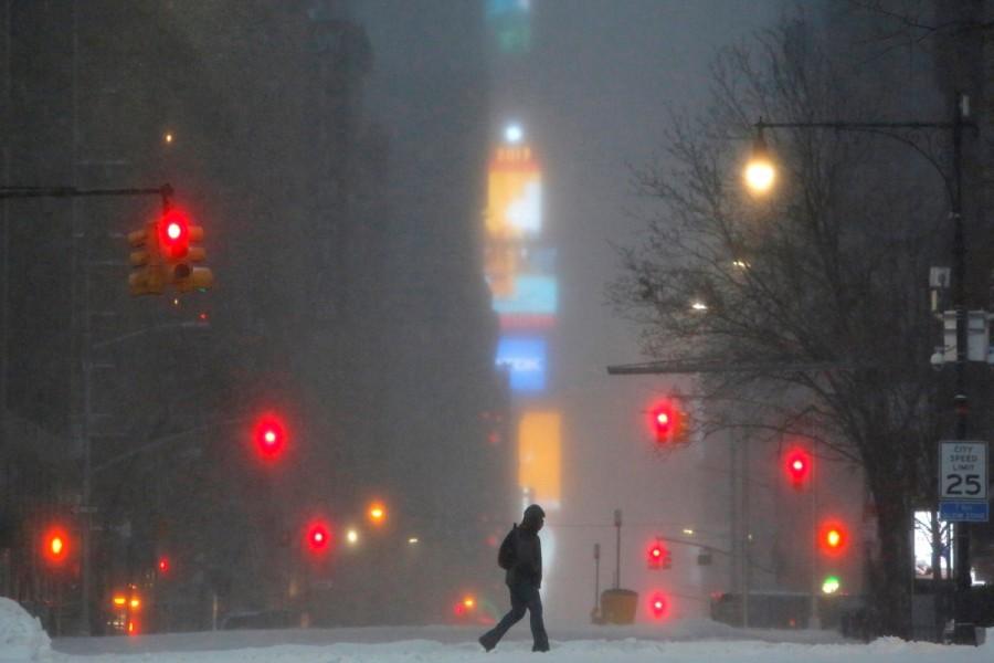 Times Square is seen in the background as a man walks along West 59th street in falling snow in Manhattan. Blizzard blankets,Snow blankets,Blizzard blankets the Northeast,northeastern United States,United States,Snow at United States