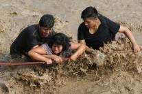 People cross a flooded street after a massive landslide and flood in the Huachipa district of Lima, Peru March 17, 2017.