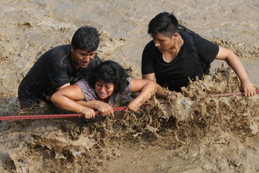 People cross a flooded street after a massive landslide and flood in the Huachipa district of Lima, Peru March 17, 2017. Floods,landslides,Floods in Peru,landslides in Peru,Peru floods
