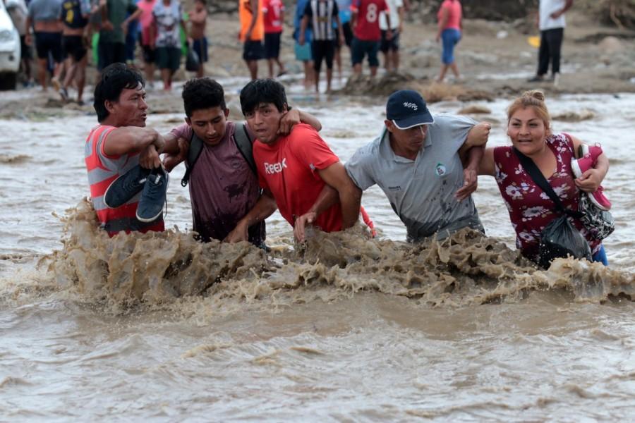 Residents cross the Viru river after Viru bridge at the Pan American highway collapsed after a massive landslide and flood in Trujillo, northern Peru. Peru,Peru floods,Peru landslides,Floods,landslides spread havoc in Peru,Floods,landslides in Peru