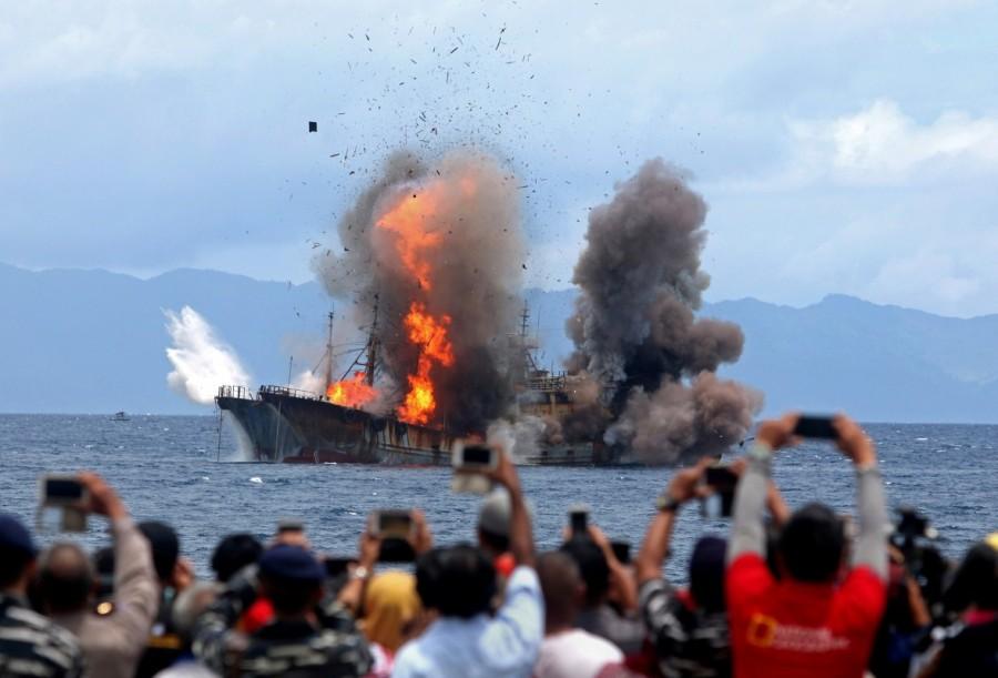 People take pictures of a burning ship as the government destroyed foreign boats that had been caught illegally fishing in Indonesia waters, at Morela village in Ambon island, April 2017. Indonesia destroyed 81 mostly foreign boats on the weekend that had been caught illegally fishing in its waters, taking to more than 300 the number sunk since President Joko Widodo launched a battle against the poaching of fish in 2014. Indonesia,illegal fishing boats,fishing boats,destroys illegal fishing boats,Indonesian navy