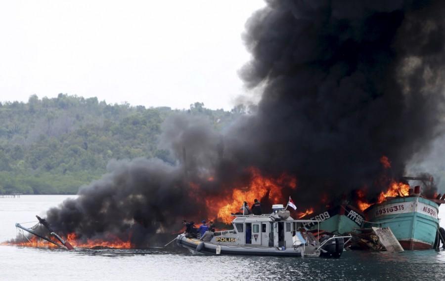 An Indonesian police boat is seen near Malaysian and Vietnamese fishing boats as they are destroyed for illegal fishing by the Ministry of Maritime Affairs and Fisheries, police and navy in Batam, Riau Islands. Indonesia,illegal fishing boats,fishing boats,destroys illegal fishing boats,Indonesian navy