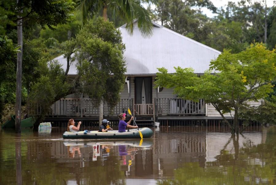 Locals float past a house in a boat on a flooded street in the northern New South Wales town of Lismore, Australia. Queensland,Australia after Cyclone Debbie,Cyclone Debbie,Cyclone Debbie effect,flood in Australia,Australia flood,australia flooding