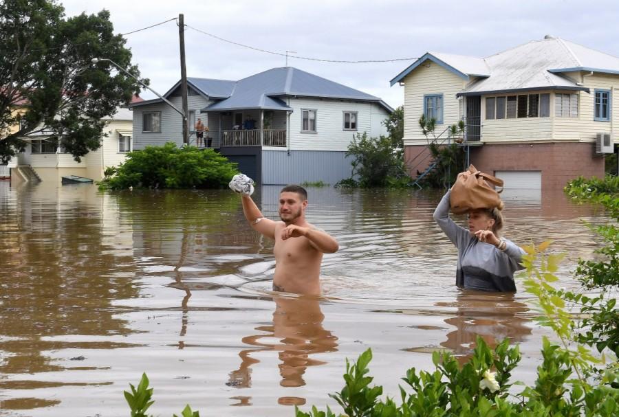 Local residents wade through floodwaters near their homes in the northern New South Wales town of Lismore. Queensland,Australia after Cyclone Debbie,Cyclone Debbie,Cyclone Debbie effect,flood in Australia,Australia flood,australia flooding