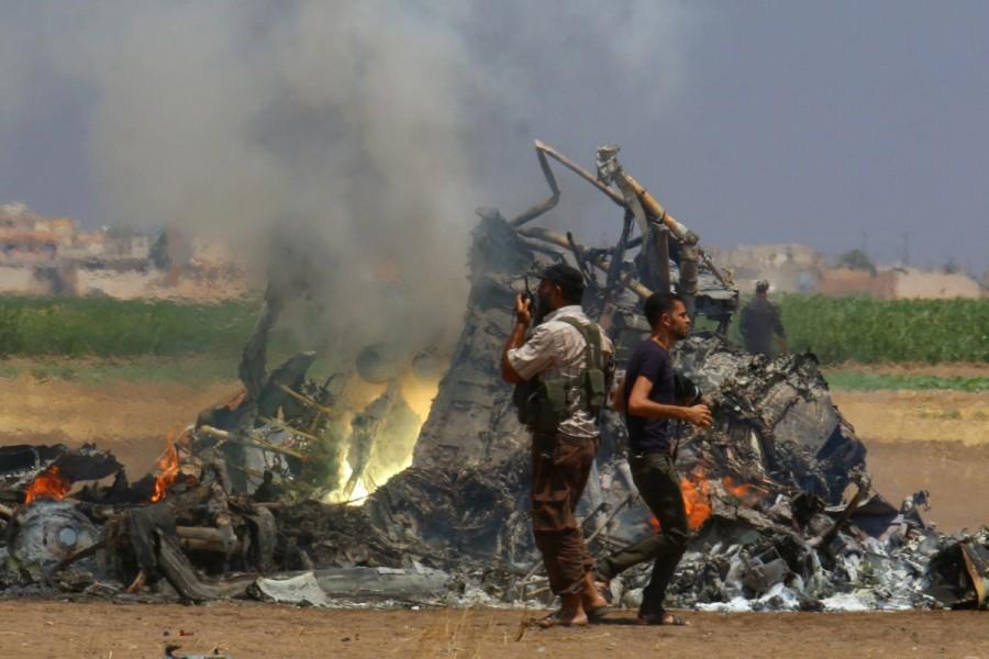 Men inspect the wreckage of a Russian helicopter shot down in the north of Syria's rebel-held Idlib province. Russian forces in Syria,Russian forces,Syria,war on Assad,Russia,Syrian government