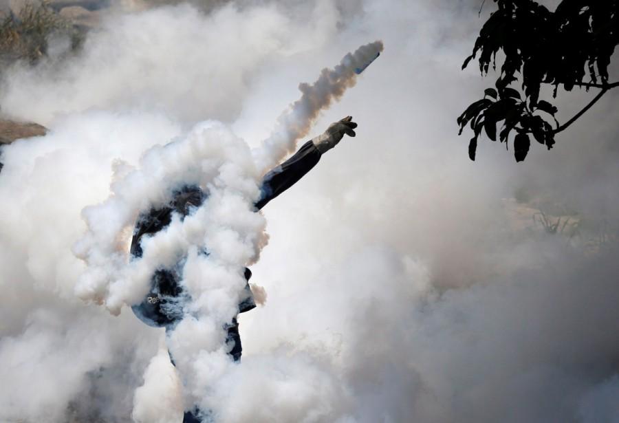 A demonstrator throws back a tear gas grenade while clashing with riot police during the so-called "mother of all marches" against Venezuela's President Nicolas Maduro in Caracas. Mother of all marches,Venezuela,President Nicolas Maduro,Nicolas Maduro,violent demonstrations,demonstrations