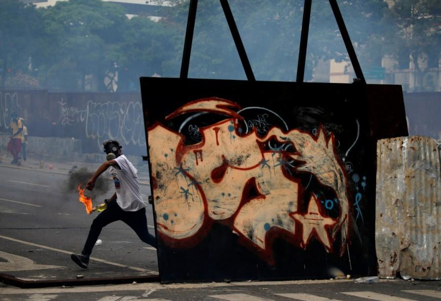 An opposition demonstrator throws a petrol bomb while clashing with riot police during the so called "mother of all marches" against Venezuela's President Nicolas Maduro in Caracas, Venezuela, April 19, 2017. Mother of all marches,Venezuela,President Nicolas Maduro,Nicolas Maduro,violent demonstrations,demonstrations
