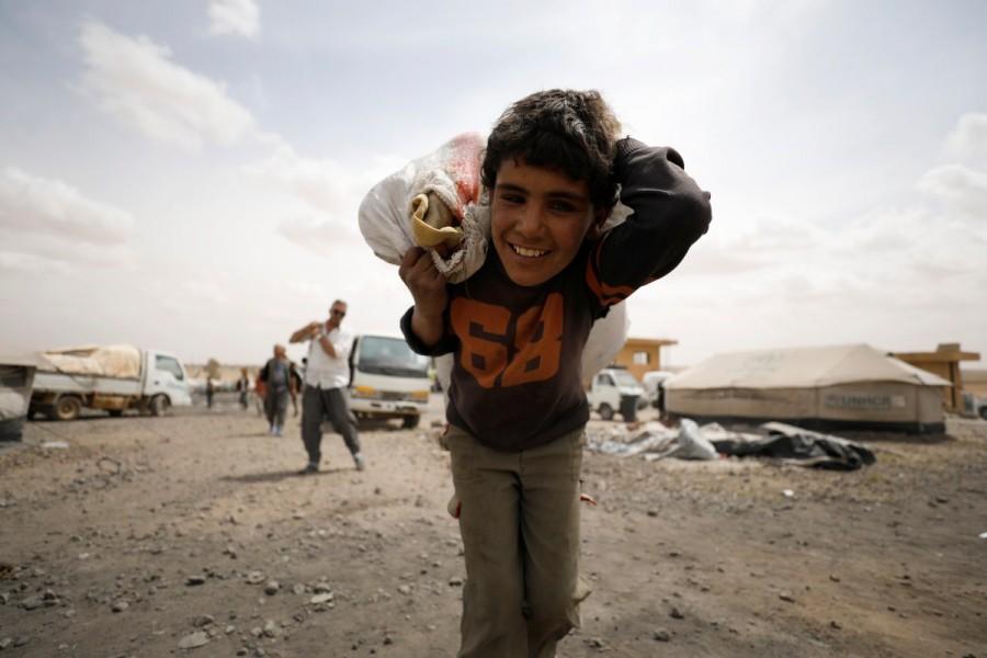 An internally displaced Syrian boy who fled Raqqa city, reacts while carrying a bag on his back inside a camp in Ain Issa, Raqqa Governorate, Syria May 2, 2017. Raqqa assault,Residents flee Islamic State,Islamic State,Raqqa,Syrian Democratic Forces