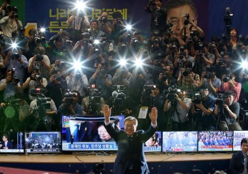 Moon Jae-in gestures to his party members as they watch a television report on a presidential election exit poll in Seoul, South Korea.