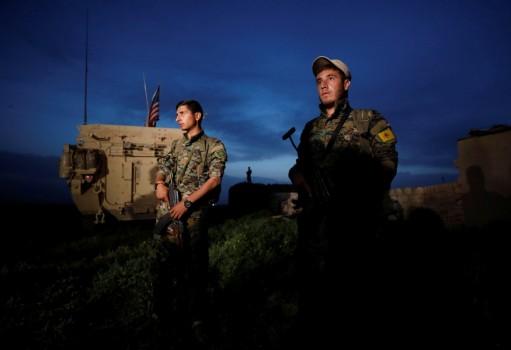 Kurdish fighters from the People's Protection Units (YPG) stand near a U.S military vehicle in the town of Darbasiya next to the Turkish border, Syria April 28, 2017.