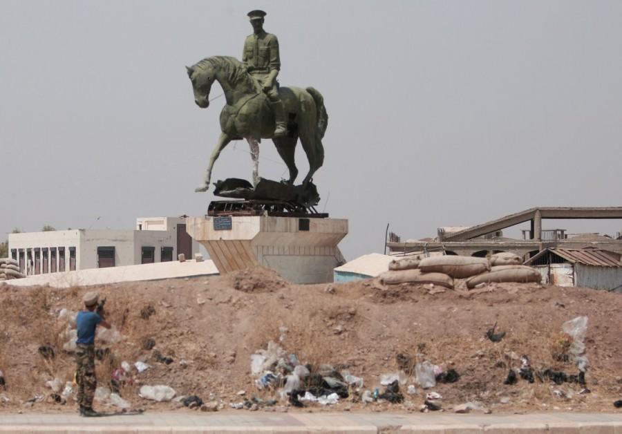 A Kurdish fighter from the People's Protection Units (YPG) fires his weapon at a statue of Bassel al-Assad, brother of Syria's President Bashar, in the Ghwairan neighborhood of Hasaka, Syria, August 22, 2016. Kurdish YPG fighter,Syria,NATO ally Turkey,NATO,Turkey,Kurdish YPG fighters,Syrian city,Raqqa,Islamic State