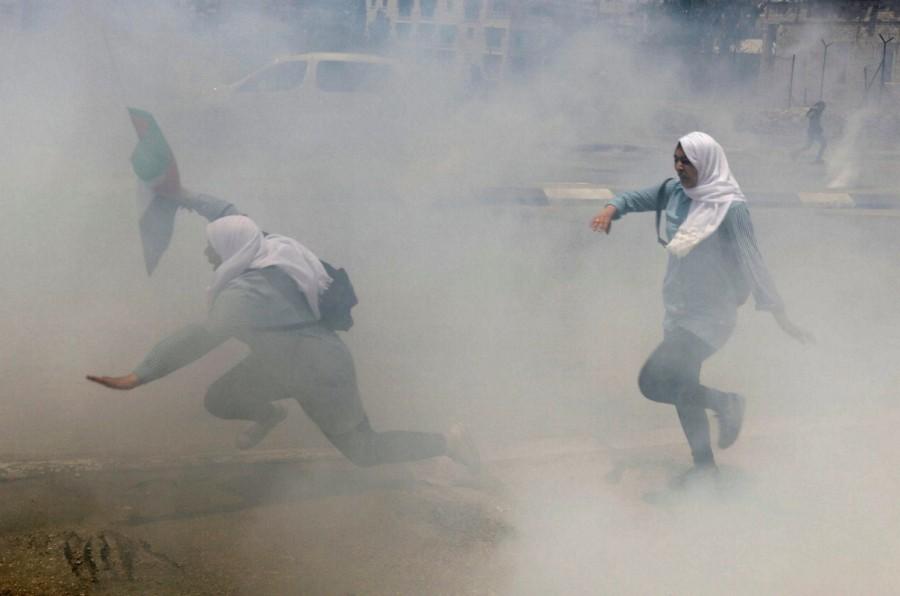 Palestinian school girls run for cover from tear gas fired by Israeli troops during clashes at a protest marking the 69th anniversary of Nakba, in the West Bank town of Bethlehem. Palestinians protest,Palestinians and Israeli forces,Israeli forces,Israel,Israel formation,israel-palestine conflict