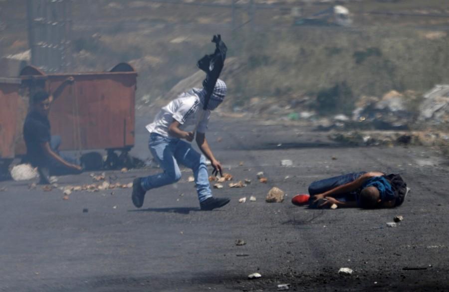 A wounded Palestinian protester lies on the ground during clashes with Israeli troops at a protest marking the 69th anniversary of Nakba, near the Jewish settlement of Beit El, near the West Bank city of Ramallah. Palestinians protest,Palestinians and Israeli forces,Israeli forces,Israel,Israel formation,israel-palestine conflict