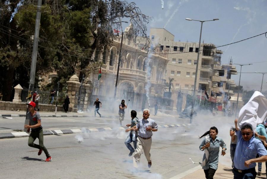 Palestinian protesters run for cover from tear gas fired by Israeli troops during clashes at a protest marking the 69th anniversary of Nakba, in the West Bank town of Bethlehem. Palestinians protest,Palestinians and Israeli forces,Israeli forces,Israel,Israel formation,israel-palestine conflict