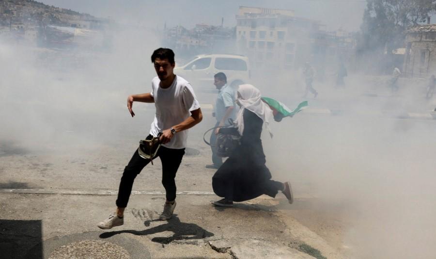 Palestinian protesters run for cover from tear gas fired by Israeli troops during clashes at a protest marking the 69th anniversary of Nakba, in the West Bank town of Bethlehem. Palestinians protest,Palestinians and Israeli forces,Israeli forces,Israel,Israel formation,israel-palestine conflict