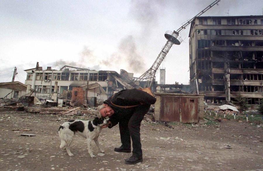 A man pats a dog in front of local red cross office and police station destroyed in last night's NATO air strikes on Kosovo's capital Pristina March 29. Residents of Pristina, capital of the southern Serb province, reported huge explosions throughout the province overnight. Jets were visible in the skies over Pristina and the aircraft flew very low, witnesses said. Treaty Organization,North American Treaty Organization,NATO in the modern world,NATO