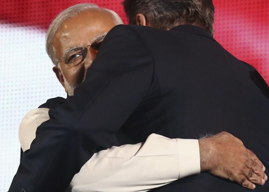 India's Prime Minister Narendra Modi (L) embraces British Prime Minister David Cameron (R) after Cameron's speech on stage at Wembley Stadium in London on November 13, 2015 during a welcome rally for Modi. Prime Minister Narendra Modi,Narendra Modi,Narendra Modi hugs,Modi special,3 years of Modi,3 years of Narendra Modi
