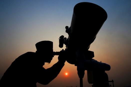 An official looks through a telescope for the sighting of the new moon for the start of Ramadan at a religious boarding school in Jakarta, Indonesia May 26, 2017.