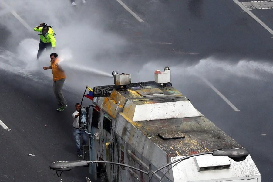 Deputy of the opposition Carlos Paparoni is hit by a jet of water during riots at a march to state Ombudsman's office in Caracas. Venezuela turns water cannons,Venezuela,Venezuela riot police,water cannons,anti-government protesters,protesters