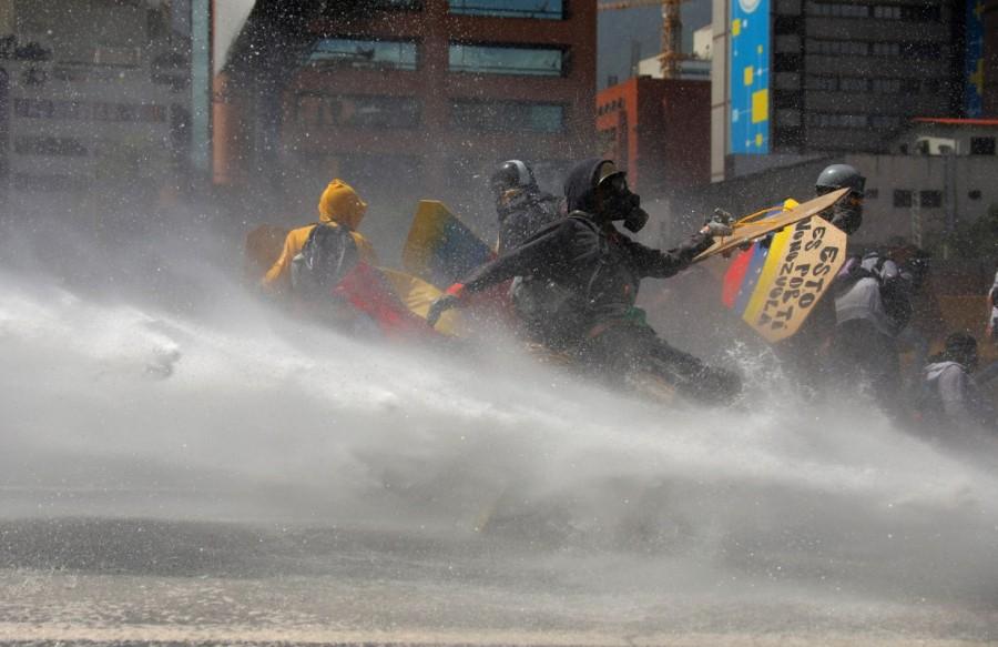 Opposition supporters clash with riot security forces while rallying against President Nicolas Maduro in Caracas. Venezuela turns water cannons,Venezuela,Venezuela riot police,water cannons,anti-government protesters,protesters