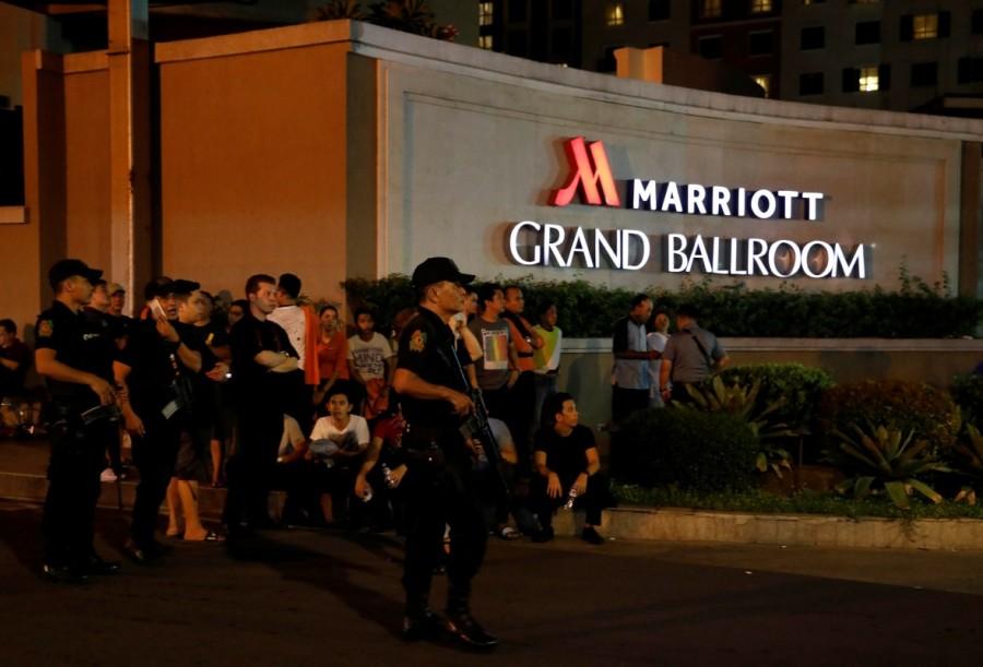 Policemen stand guard near evacuated employees of a hotel near a situation at a Resorts World building, in Pasay City, Metro Manila, Philippines. Gun shots,explosions in Manila,Manila,Explosions in Manila,gunshots in Manila,gunshots at resort,gunshots at resort in Manila
