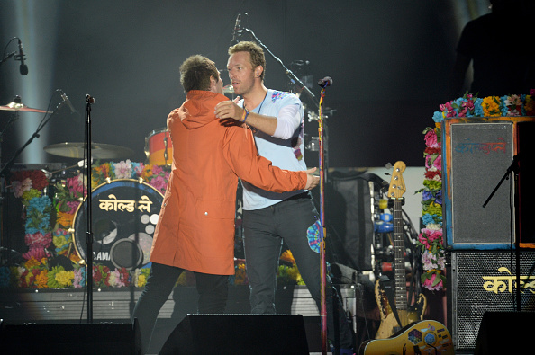 Liam Gallagher hugs Chris Martin on stage on June 4, 2017 in Manchester, England. Liam Gallagher,Chris Martin,Ariana Grande,Miley Cyrus,One Love Manchester Benefit Concert,One Love Manchester
