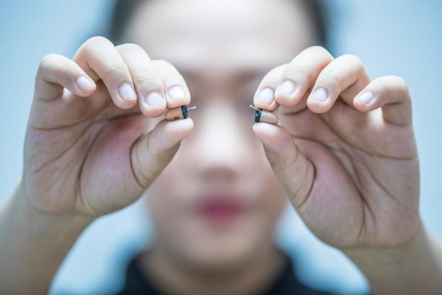 A woman holds a pair of earpieces during a presentation to the media. Devices used to cheat exams,cheat exams,High-tech devices used to cheat China's exams,High-tech devices used to cheat exams,High-tech devices
