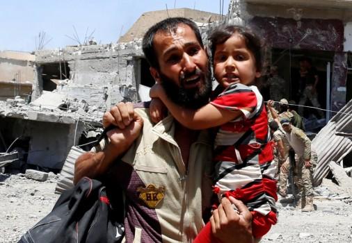 A man displaced by fighting between Iraqi forces and Islamic State militants carries his daughter in Mosul's al-Zanjili's district.