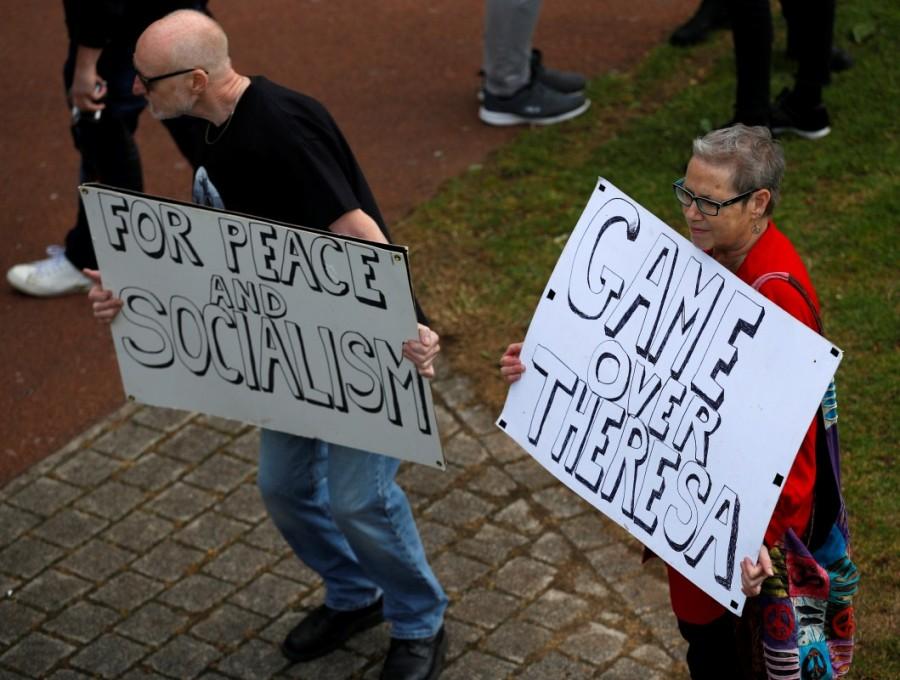 Supporters hold placards ahead of the arrival of Labour Party leader, Jeremy Corbyn, for an election rally in Runcorn. Britain's Prime Minister,Theresa May,Britain's Prime Minister Theresa May,Britain Prime Minister Theresa May,Labour Party,Jeremy Corbyn,UK campaign trail,UK General election,UK General election 2017