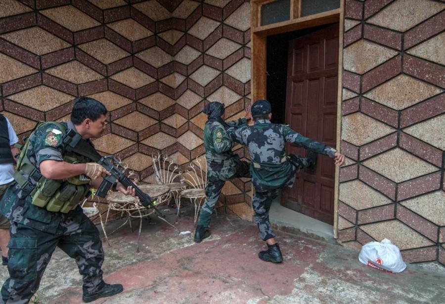 A joint group of police and military forces kick a door while conducting a house to house search as part of clearing operations in different sections of Marawi city. Philippines battles Islamist fighters,Islamist fighters,Marawi City,Islamic State,Syria,Iraq,Philippine island