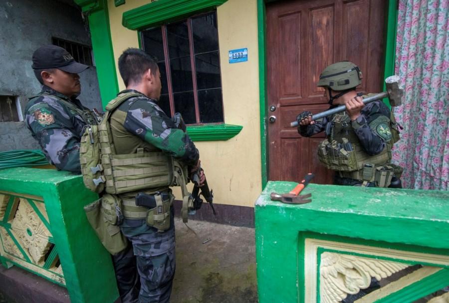 A joint group of police and military forces use a mallet to open a door while conducting a house to house search as part of clearing operations in different sections of Marawi city. Philippines battles Islamist fighters,Islamist fighters,Marawi City,Islamic State,Syria,Iraq,Philippine island
