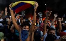 Protesters react in front of a fire burning at the entrance of a building, housing the magistracy of the Supreme Court of Justice and a bank branch, during a rally against Venezuela's President Nicolas Maduro, in Caracas, Venezuela June 12, 2017.