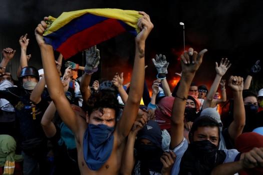 Protesters react in front of a fire burning at the entrance of a building, housing the magistracy of the Supreme Court of Justice and a bank branch, during a rally against Venezuela's President Nicolas Maduro, in Caracas, Venezuela June 12, 2017.