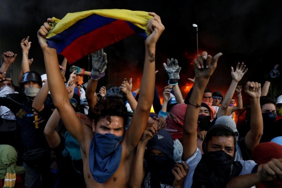 Protesters react in front of a fire burning at the entrance of a building, housing the magistracy of the Supreme Court of Justice and a bank branch, during a rally against Venezuela's President Nicolas Maduro, in Caracas, Venezuela June 12, 2017. Venezuela Supreme Court office,Protesters attack Venezuela Supreme Court office,Protesters angry
