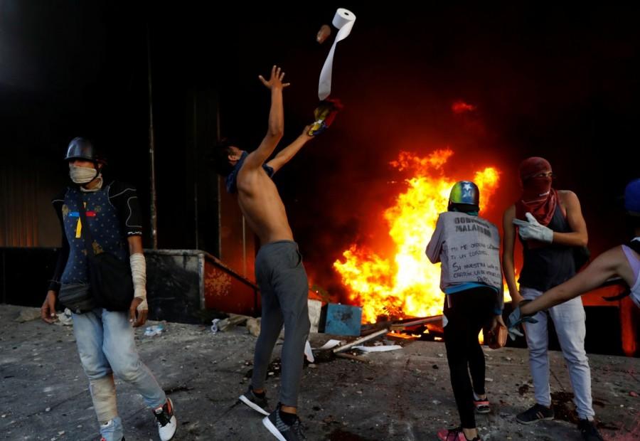 Protesters stand outside a burning bank branch, housed in the magistracy of the Supreme Court of Justice, during a rally against Venezuela's President Nicolas Maduro, in Caracas. Venezuela Supreme Court office,Protesters attack Venezuela Supreme Court office,Protesters angry
