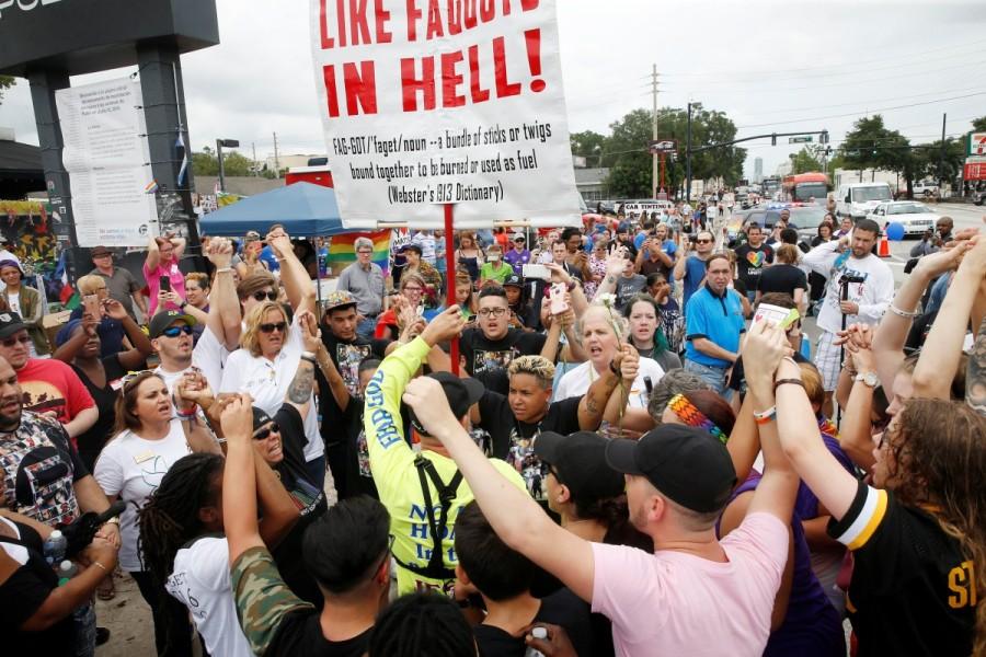 Guests visiting the memorial outside the Pulse Nightclub on the one-year anniversary of the shooting raise their hands around a protester in Orlando, Florida. Orlando,Orlando Pulse nightclub massacre,Pulse nightclub massacre,Pulse nightclub,first anniversary of Orlando's Pulse nightclub,Pulse Nightclub,pulse nightclub shooting