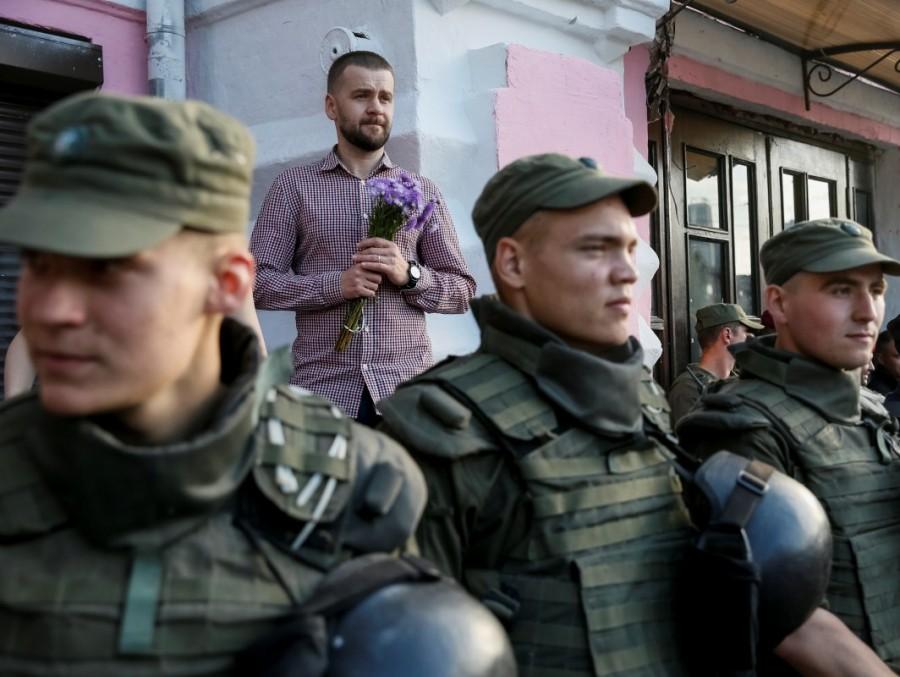 An LGBT activist is seen before the opening ceremony of Kiev Pride 2017 as servicemen of the National Guard stand guard in Kiev. Rainbow flag burned,Ukraine Pride event,Anti-LGBT protesters,Kiev Pride 2017,Ukrainian capital,Anti-LGBT protesters burned a rainbow flag