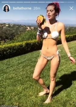 American actress and singer Bella Thorne flaunts her ample cleavage in white thong bikini as she poses with burger in hand.