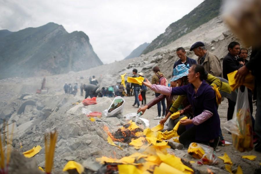 Relatives of victims burn incense and paper money to mourn their dead relatives at the site of a landslide in the village of Xinmo, Mao County, Sichuan Province. Landslide buries Chinese village,Chinese village,Sichuan province,Xinmo village,Xinmo village China landslide