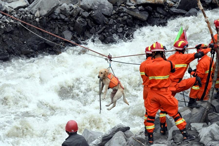 Rescue workers pull a rescue dog across a river at the site of a landslide in the village of Xinmo, Mao County, Sichuan Province. Landslide buries Chinese village,Chinese village,Sichuan province,Xinmo village,Xinmo village China landslide
